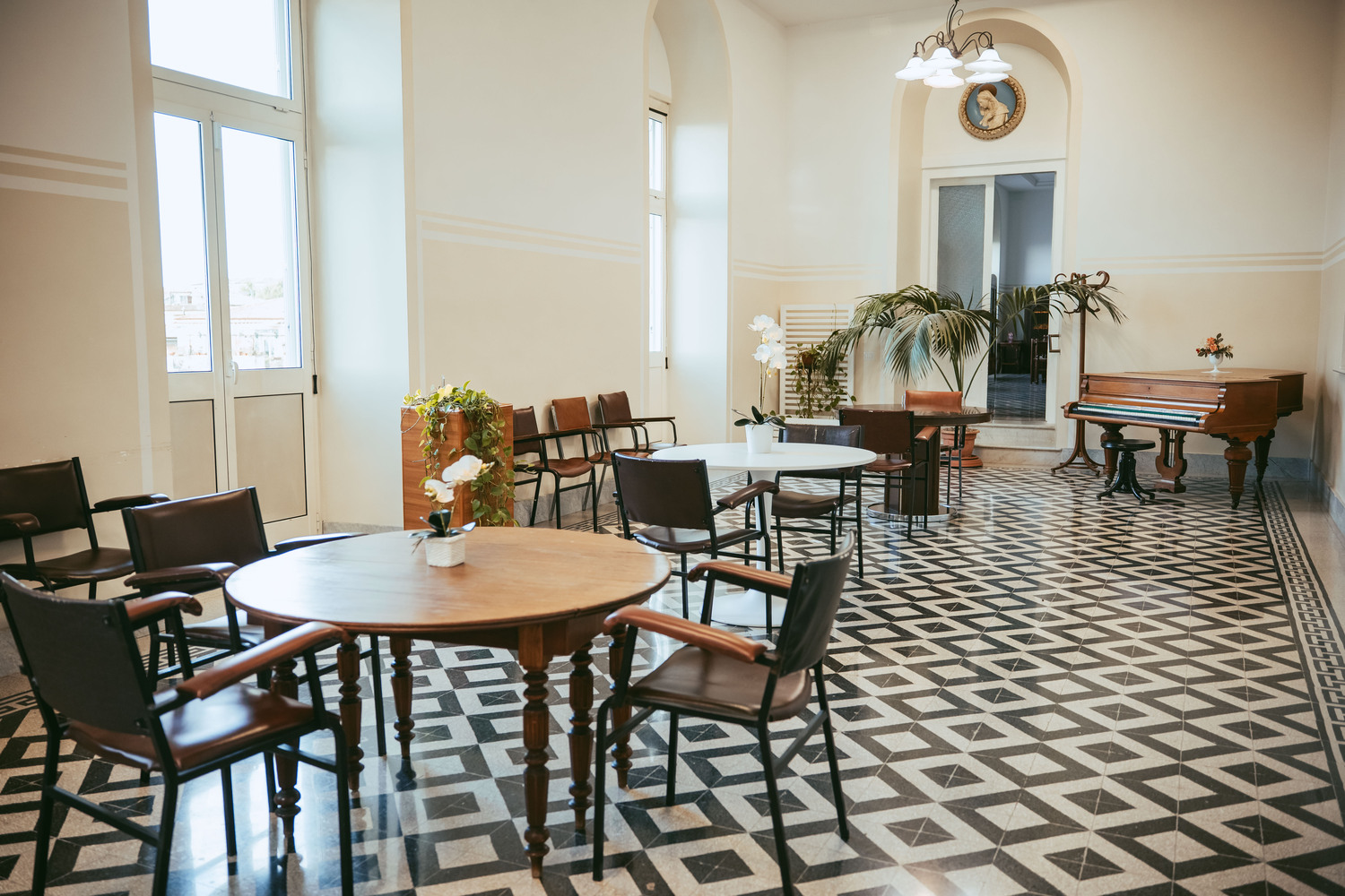 Sala comune luminosa con tavoli e pianoforte